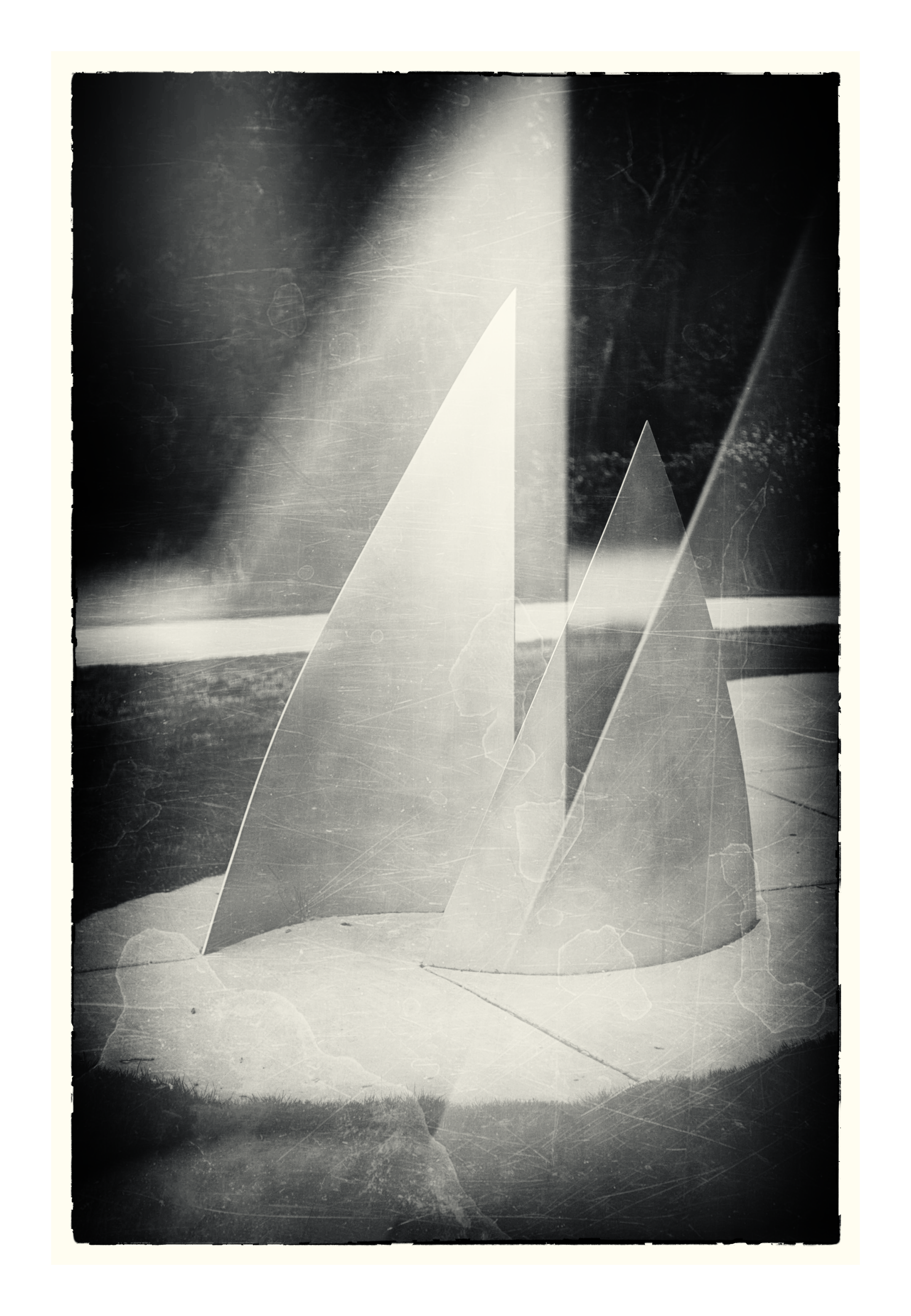 Abstract black and white image of translucent triangular forms layered against light and shadow.